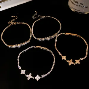 Macro view of four 18k gold plated zircon and pearl flower bracelets on black background