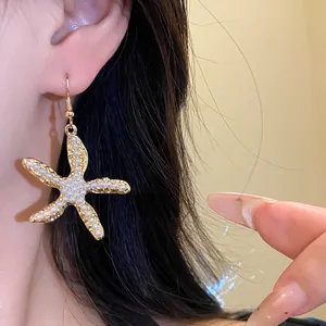 Detailansicht eines luxuriösen Seestern-Ohrrings mit Perlen, getragen von einem Modell
