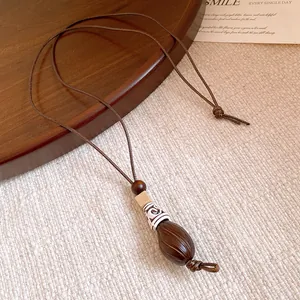 Detailed view of a vintage ethnic style resin pendant on a long brown cord necklace.