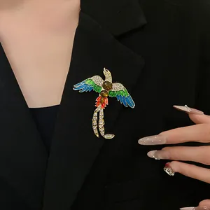 Close-up of a vintage bird brooch with colorful enamel and sparkling crystals on black blazer