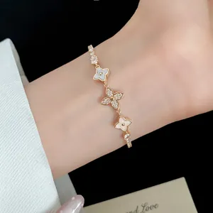 Close-up of an elegant 18k gold plated bracelet with zircon clover flowers worn on a wrist