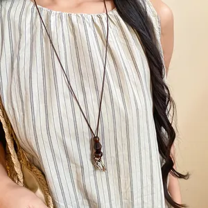 Detail of a vintage ethnic long necklace with wooden beads and resin pendant on a model.
