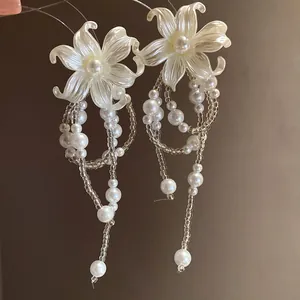 Detail view of elegant pearl flower earrings with long beaded tassels for vacation.