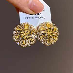 Intricate gold plated flower stud earrings with sparkling yellow and white stones close-up view