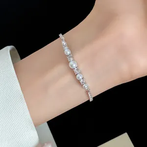 Elegant silver-tone bracelet featuring pearls and zircons worn on a wrist.