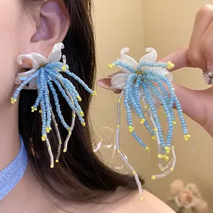 Close-up of elegant flower tassel earrings featuring blue beads and silver needles for women