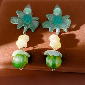 Dettaglio di orecchini a fiore in resina con perline di marmo verde su velluto