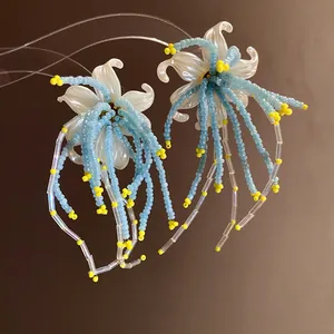 Macro view of flower tassel earrings with blue seed beads and yellow accents