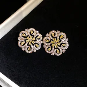Close-up of hollow floral earrings with yellow stones in a black velvet jewelry box