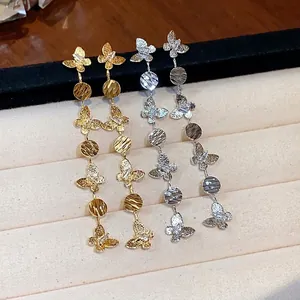 Pair of gold and silver butterfly tassel earrings displayed on a beige jewelry tray.