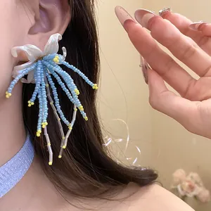 Macro view of light blue beaded tassel earrings showing intricate beadwork and floral base