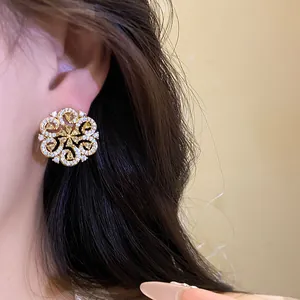Detail shot of elegant hollow gold flower stud earrings with yellow and white stones