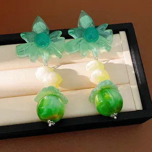 Dettaglio di orecchini a fiore in resina verde con finitura marmorea in scatola nera