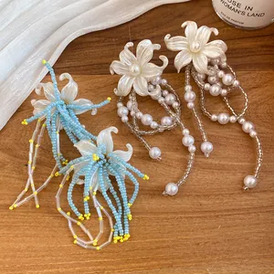 Close-up of pearl flower tassel earrings with intricate beadwork and silver needles