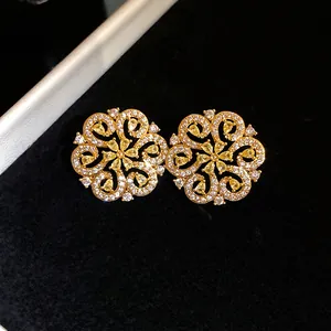 Detailed macro shot of elegant golden hollow flower earrings with shimmering yellow crystals.