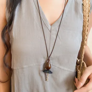 Detailed view of a retro ethnic long necklace with wood bead and resin pendant on model