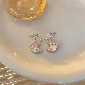 Detalle de pendientes de manzana esmaltados con flores rosas y piedras de circón