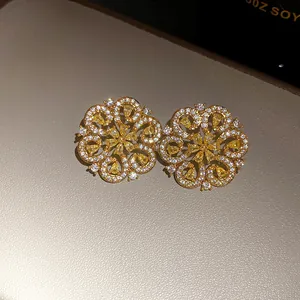Macro detail of gold plated flower stud earrings with yellow and clear cubic zirconia stones.