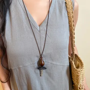 Detail view of long retro ethnic necklace with wooden bead and resin pendant on model