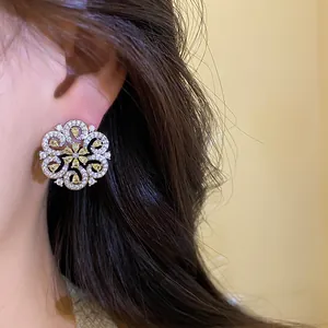 Detailed close-up of intricate hollow floral stud earrings with yellow crystals.