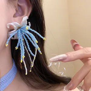 Exquisite handmade light blue beaded tassel earrings with white floral detail on model