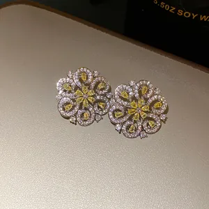 Close-up macro detail of French style hollow flower stud earrings with sparkling yellow crystals