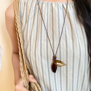 Detailed view of a retro long necklace with wooden beads and amber resin leaf pendants.