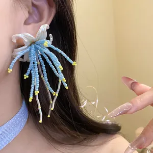 Detail view of an elegant floral earring with blue beaded tassels and yellow accents.