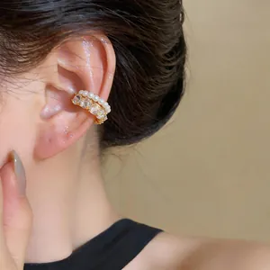 Detailed view of a multi-layer gold ear cuff with pearls and clear zirconia stones.