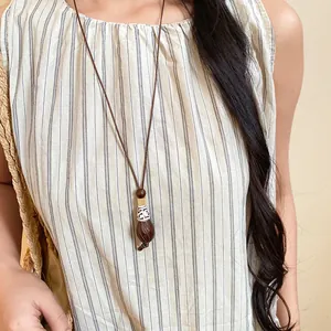 Detailed shot of a vintage ethnic long necklace with wooden bead and resin pendant on a model