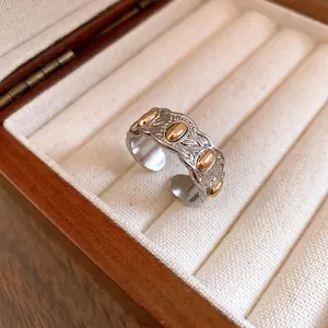 Anillo abierto plateado texturizado con detalles dorados en caja de madera elegante