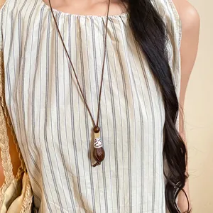 Close-up of retro ethnic long necklace with wood bead and resin pendant on model