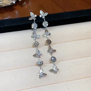 Close-up of butterfly tassel earrings with zircon stones and 18k gold plating