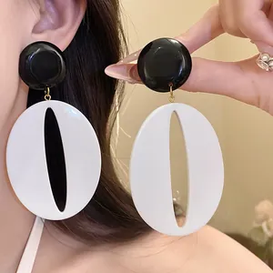 Detailed close-up of vintage black and white resin oval drop earrings worn by a model