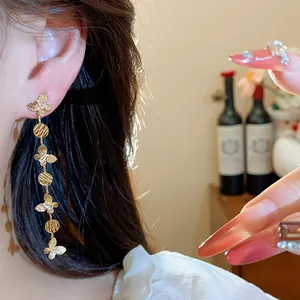 Close-up of 18k gold plated butterfly tassel earrings with zircons on model's ear