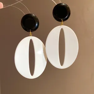 Close-up of black and white resin oval drop earrings with minimalist retro design