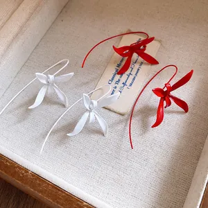 Elegant close-up of red and white painted flower ear hook earrings in a vintage box