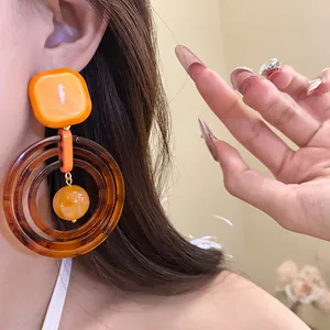Close-up of Maillard style resin drop earrings with nested amber rings worn by a model