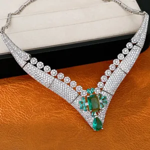 Detailed view of luxury vintage V-shaped necklace with emerald green stones and pave zircons