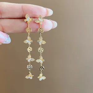 Detailed view of long gold butterfly tassel earrings with sparkling zircon crystal accents.