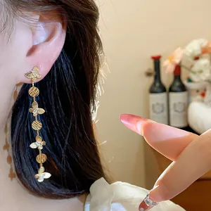 Detailed close-up showing 18k gold plated long tassel butterfly earrings worn on the ear