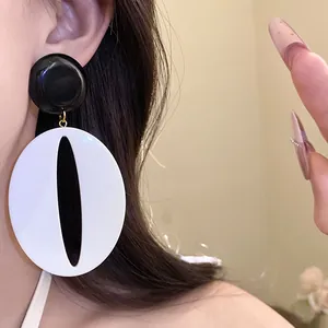 Minimalist retro black and white resin oval drop earrings worn by a model for a stylish look