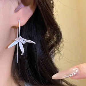 Close-up detail of a minimalist white painted metal flower ear hook earring on a model