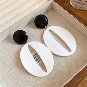 Detailed view of retro black and white resin oval hollow pendant earrings in a box