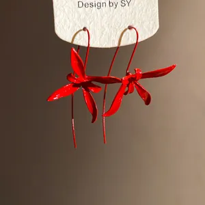 Detailed view of elegant red metal orchid earrings with a minimalist spray-paint finish