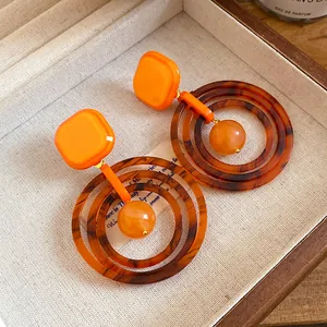 Detail of Maillard style resin earrings with tortoise shell pattern and orange accents