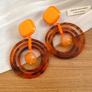 Close-up detail of retro orange and tortoiseshell resin hoop drop earrings for women