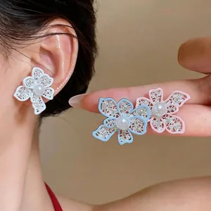 Elegant hollow flower stud earrings featuring central pearls in white, blue and pink colors