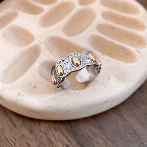 Primer plano de un anillo plateado texturizado con adornos dorados de forma ovalada