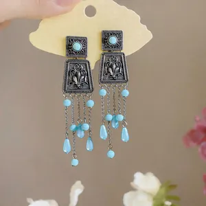Detailed close-up of vintage silver square stud earrings with blue acrylic tassels